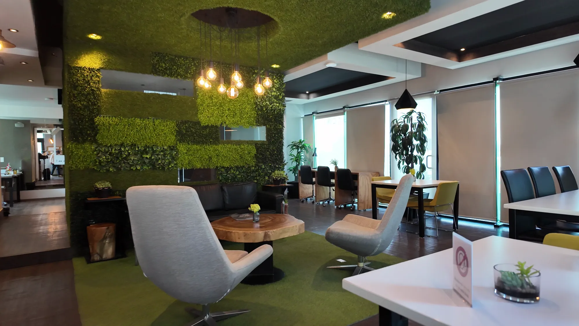 Lounge de coworking con muro verde y mobiliario moderno en Think Workspace
