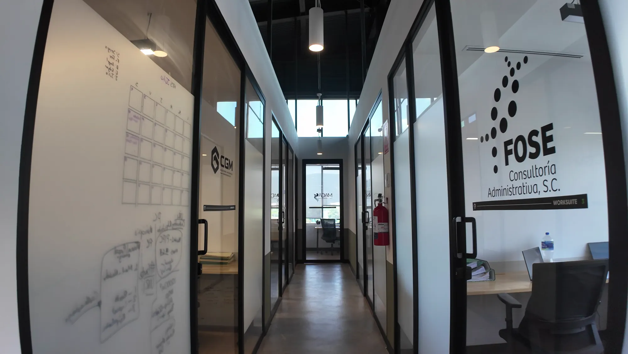 Pasillo de oficinas privadas con paredes de vidrio en Think Workspace