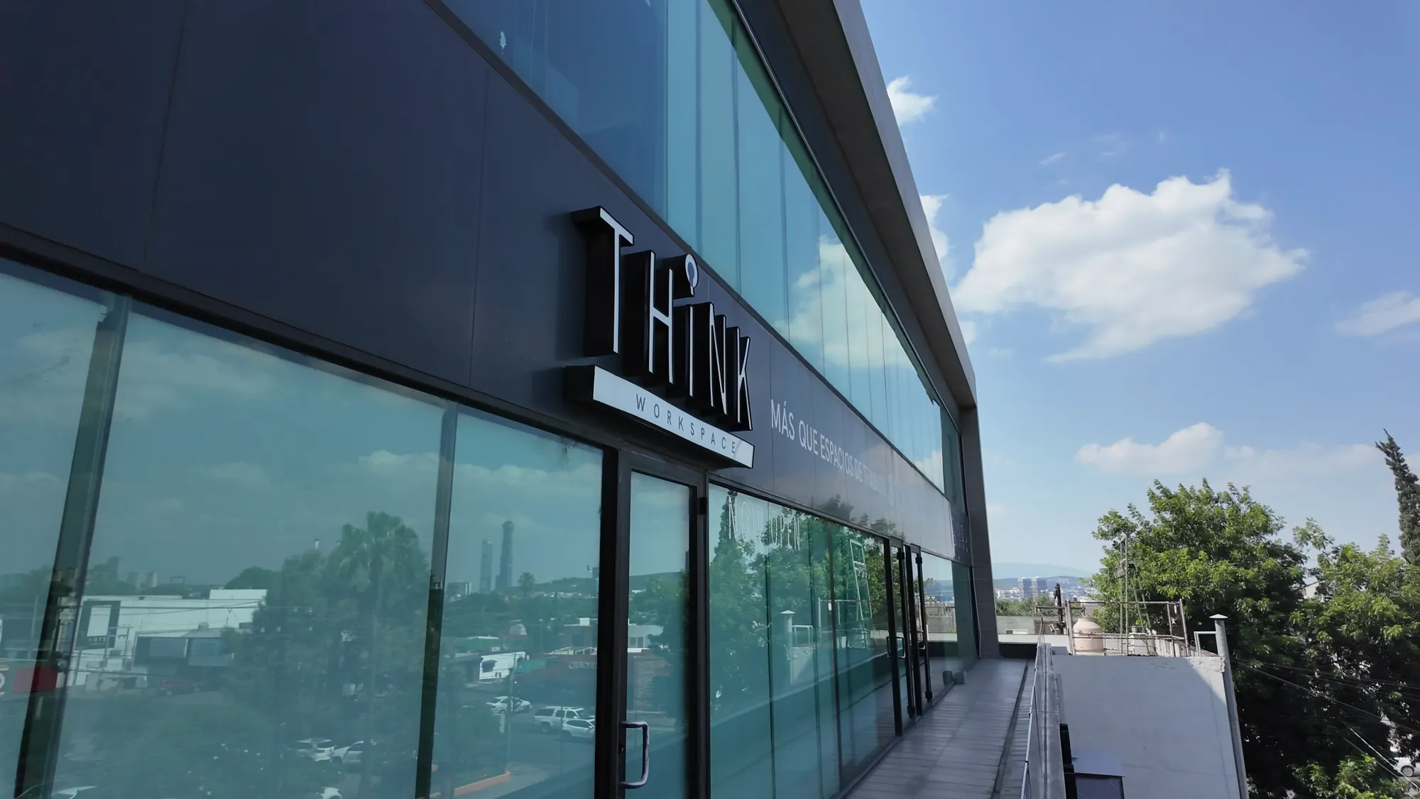 Fachada exterior de Think Workspace con letrero y vista panorámica de Monterrey